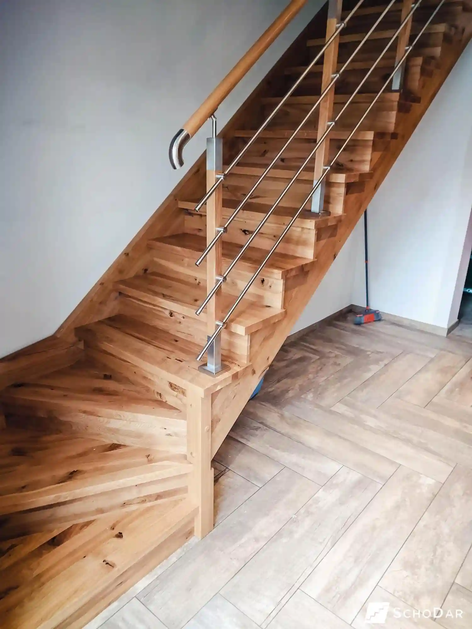 Zbliżenie na drewnianą poręcz schodów z poziomymi stalowymi prętami balustrady